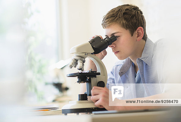 Teenage boy (16-17) looking through microscope