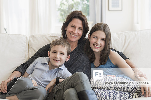 Mother and kids(8-9  10-11) sitting on sofa