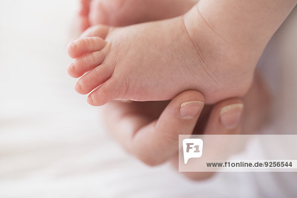 Close up of mother's hand touching baby boy's(2-5 months) foot