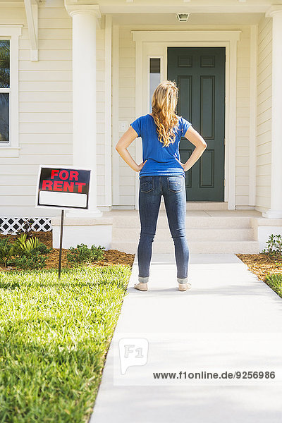 Rear view of woman standing next to for rent sign