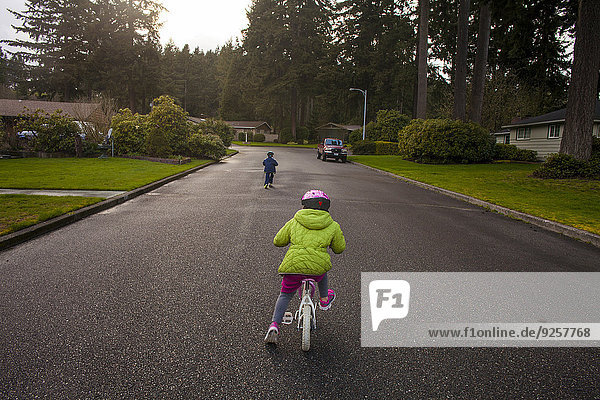 Caucasian children riding bicycles on suburban street