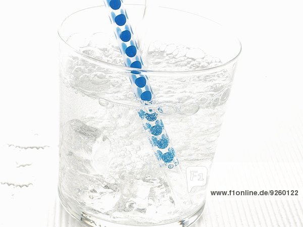 Mineralwasser im Glas mit Eiswürfeln und Strohhalm