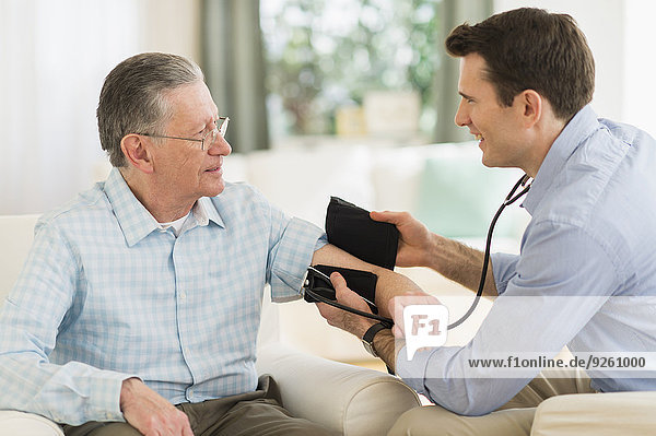 Caucasian doctor taking patient's blood pressure at home