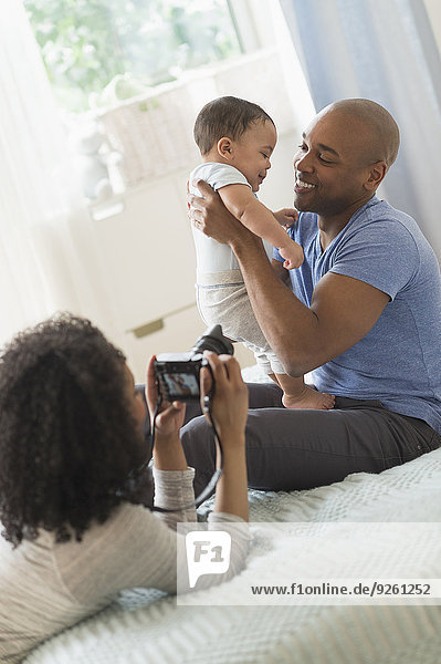 Woman taking picture of father and baby