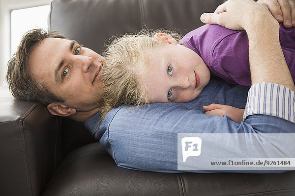 Caucasian father and daughter relaxing on sofa