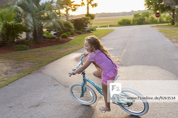 Caucasian girl riding bicycle on street