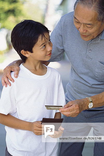 Senior Senioren Mann geben Enkelsohn Kredit Kreditkarte Karte