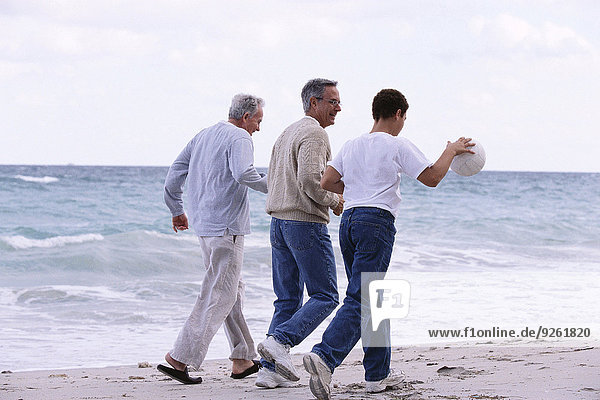 Three generations of Caucasian men walking on beach