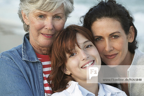 Three generations of women smiling on beach