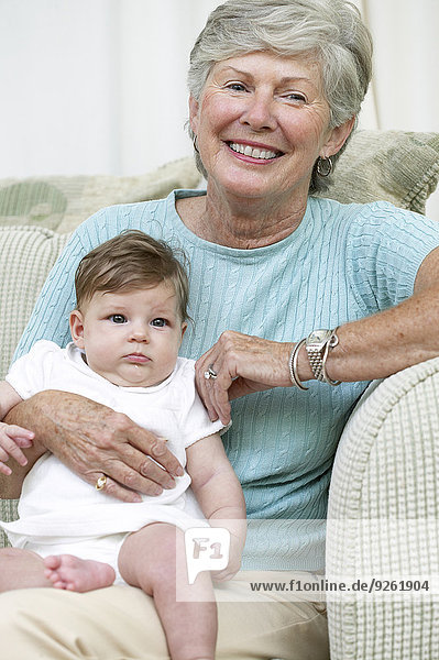 Senior woman sitting with granddaughter on sofa
