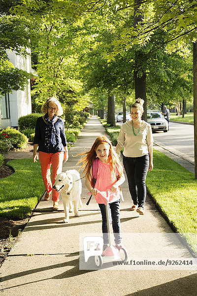 Caucasian family walking dog on suburban sidewalk