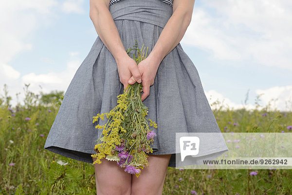 Junge Frau auf einer Wildblumenwiese mit Blumen