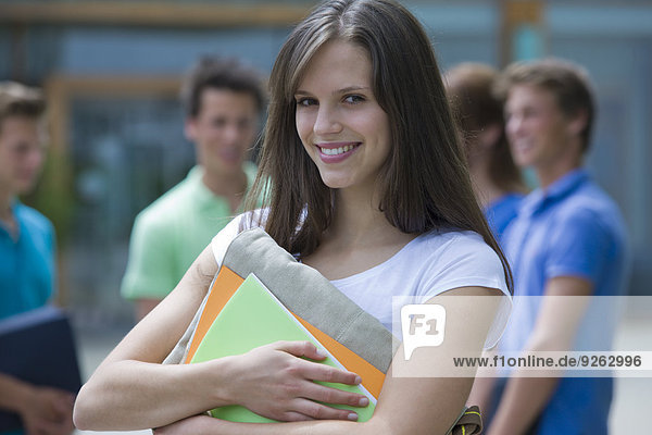 Germany  Baden-Wuertemberg  portrait of smiling young female student and her classmates in the background