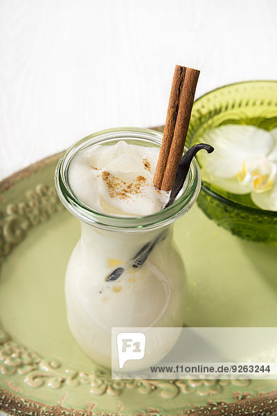 Chai Latte Eistee im Glas mit Zimtstange und Vanilleschote