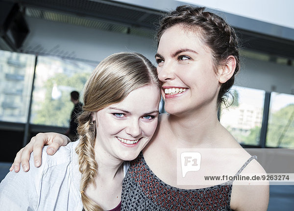 Two young women hugging at subway station
