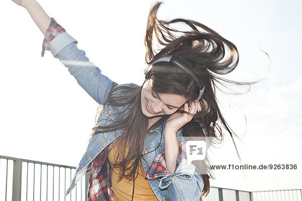 Porträt einer glücklichen jungen Frau beim Musikhören mit Kopfhörern