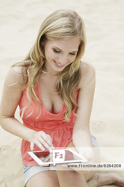 Portrait of young woman using digital tablet on the beach