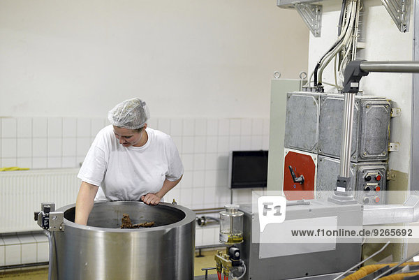 Deutschland  Sachsen-Anhalt  Frau beim Rühren der Schokoladenmischung in einem Kessel in einer Backfabrik