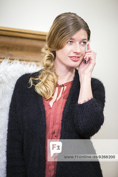Porträt einer lächelnden Frau beim Telefonieren zu Hause