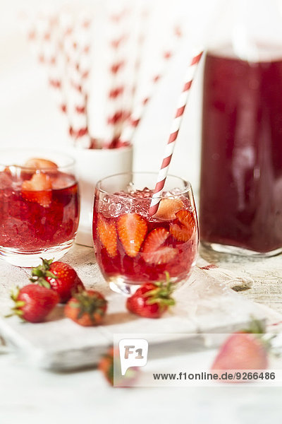 Glas eisgekühlter roter Früchtetee mit Erdbeeren und zerstoßenem Eis