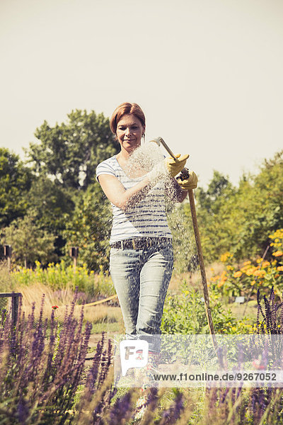Reife Frau beim Blumen gießen