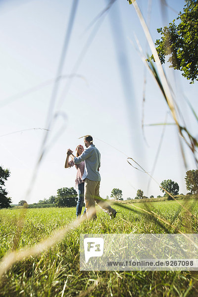 Young couple dancing together on a meadow