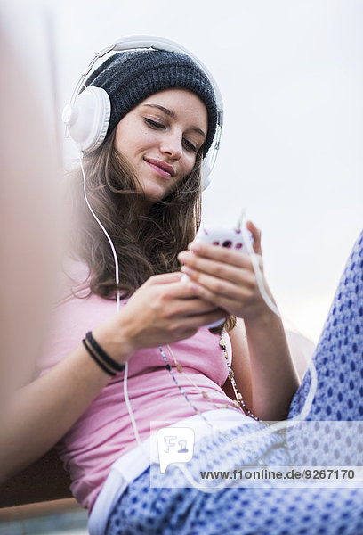 Porträt eines lächelnden Teenagermädchens mit Smartphone-Hörmusik mit Kopfhörer