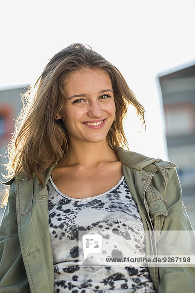 Portrait of smiling teenage girl in back light