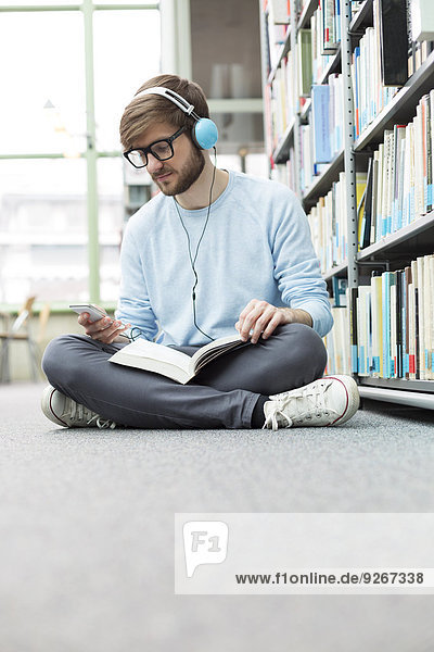 Student in a university library sitting on floor with headphones