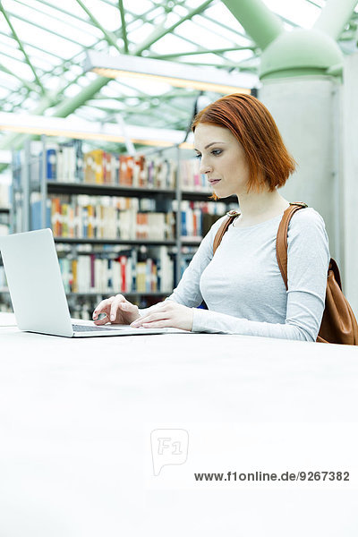 Student in einer Universitätsbibliothek mit Laptop
