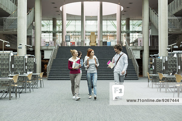 Studentengruppe zu Fuß in einer Universitätsbibliothek