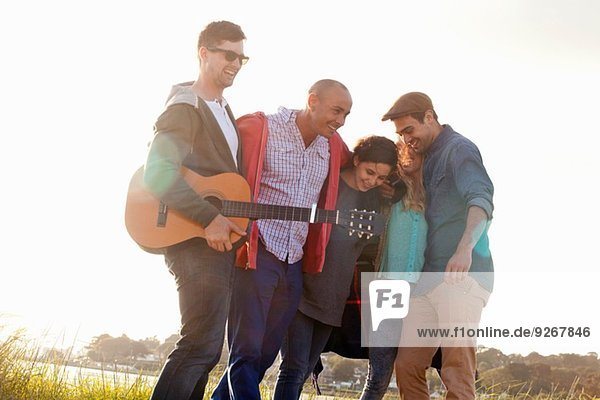 Fünf erwachsene Freunde mit akustischer Gitarre am Bournemouth Beach  Dorset  UK