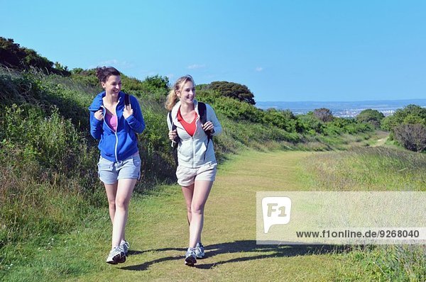 Two young women walking along coastal path