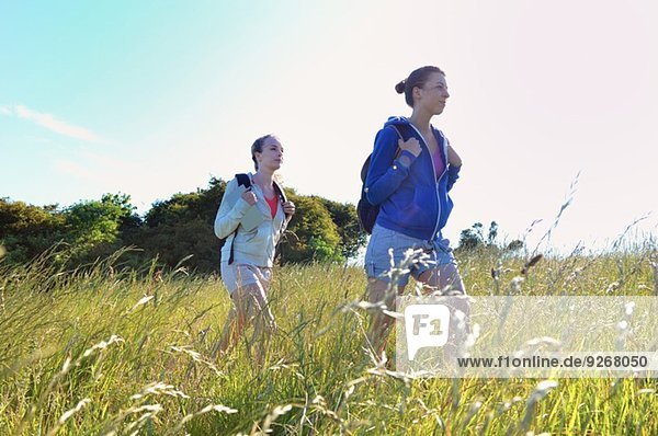 Two young women hiking through field