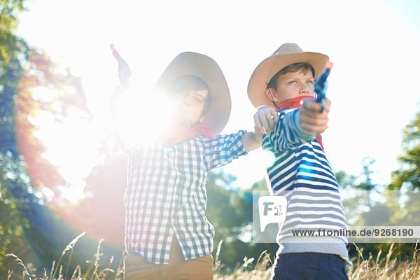 Zwei kleine Jungen als Cowboys verkleidet  die Spielzeugpistolen halten.