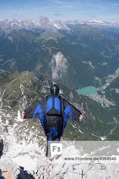 Mid adult man BASE jumping from mountain edge  Alleghe  Dolomites  Italy