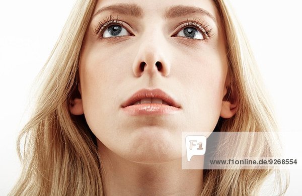 Cropped close up studio portrait of young woman gazing upward