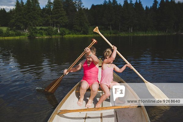 Two young sisters rowing in canoe on Indian river  Ontario  Canada
