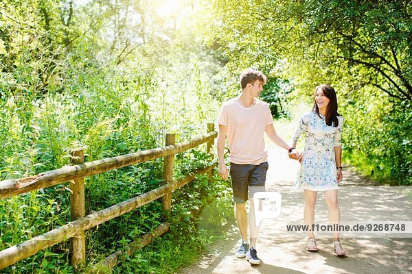 Paar über eine Holzbrücke im Park gehen