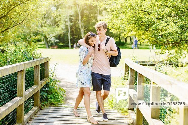 Paar über eine Holzbrücke im Park gehen