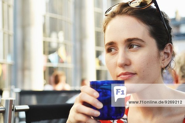 Nahaufnahme einer jungen Frau bei einem Drink im Straßencafé
