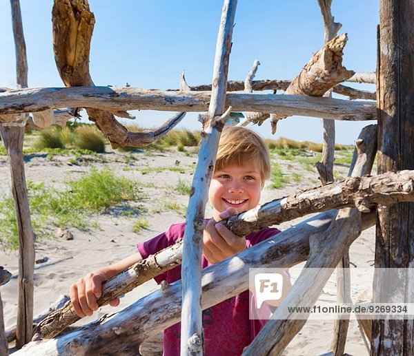 Boy placing driftwood to construct shelter  Caleri Beach  Veneto  Italy