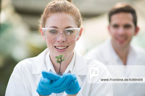Porträt einer Wissenschaftlerin  die eine Pflanzenprobe hochhält