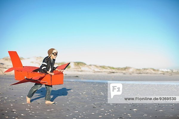 Junge rennt mit Spielzeugflugzeug am Strand Junge rennt mit Spielzeugflugzeug am Strand