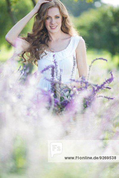 Porträt einer schönen jungen Frau auf einer Wiese mit violetten Blumen