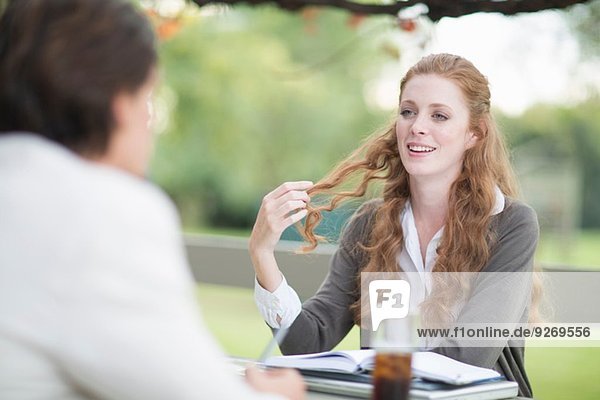 Over the shoulder view of businessman and female colleague having informal meeting in garden