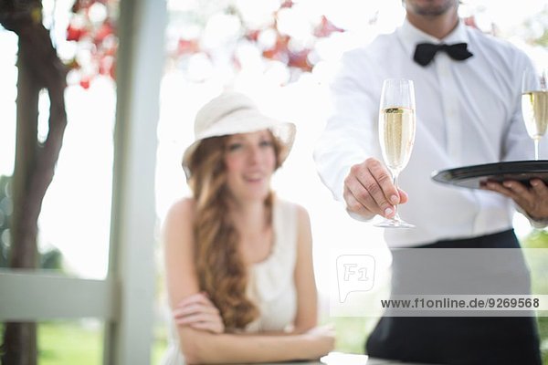 Waiter serving champagne in garden restaurant