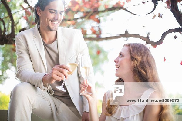 Couple toasting each other with champagne in garden restaurant