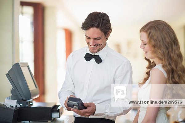 Waiter and female customer using credit card machine in restaurant