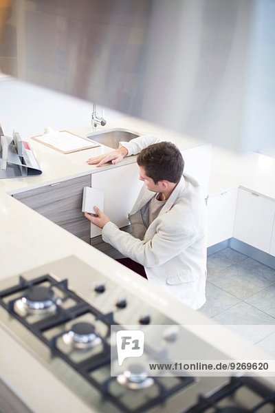 Mittlerer Erwachsener Mann beim Betrachten von Keramikfliesen im Küchen-Showroom